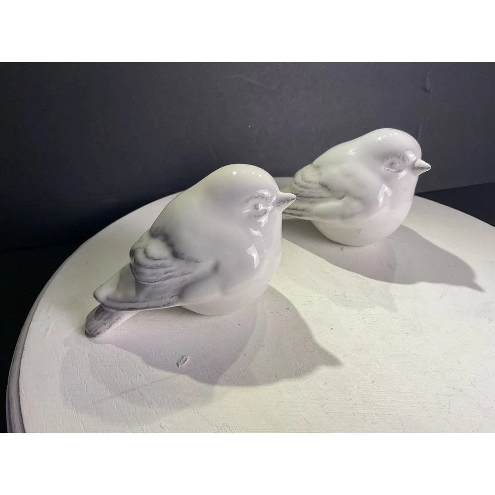 Two little bird figurines with some coloring on the feathers